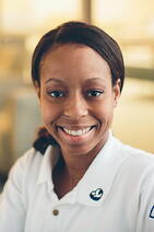 NMC nursing student smiling in a white polo with the NMC heart and dove logo on the collar