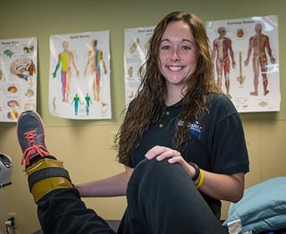Physical Therapy Assistant Student stretching out a volunteer's leg