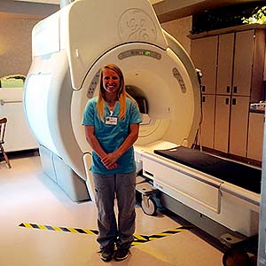 MRI Student posing in front of an MRI machine
