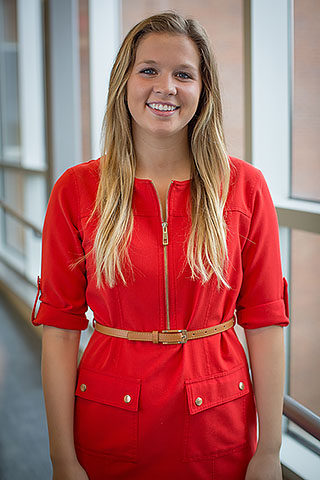 Maddie, a woman in her twenties with long blonde hair and wearing a red dress