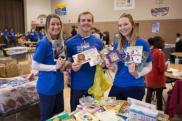 NMC nursing students with some of the free children's books available at the Minne Lusa Health Carnival.