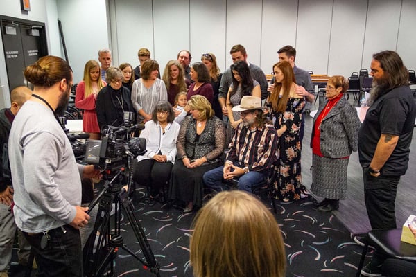 Members of the media focus TV camera on Jan Going and Stephanie Pettett, with their family members standing behind them. 