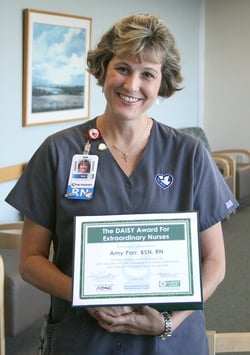 Amy Parr holds her DAISY Award certificate for excellence in nursing.