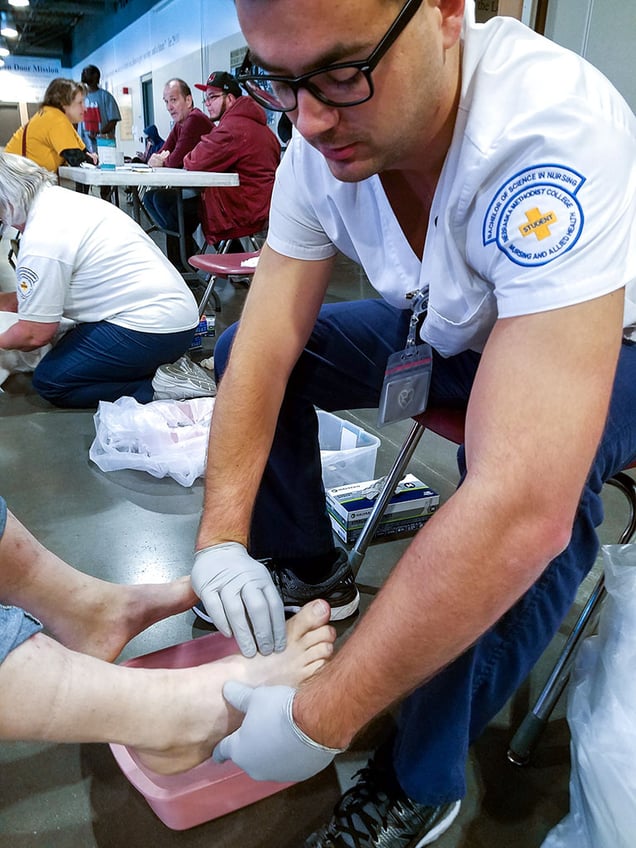 NMC nursing student Ben Troudt examines a client's foot. 