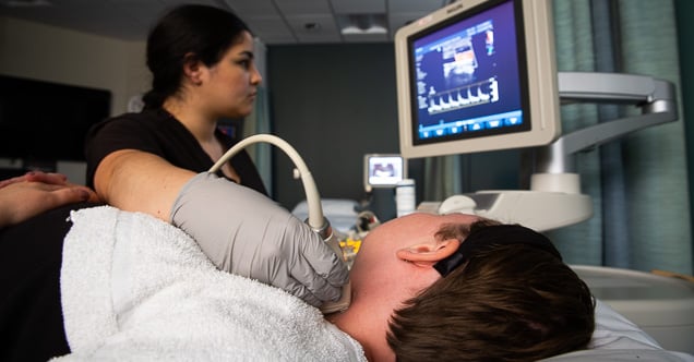 A cardiovascular sonography student performs an echocardiogram on the jugular vein in the neck.