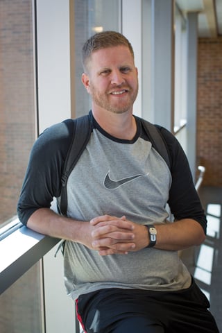 Nebraska Methodist nursing student, Shawn. Seen leaning against a window with his backpack slung around his shoulders