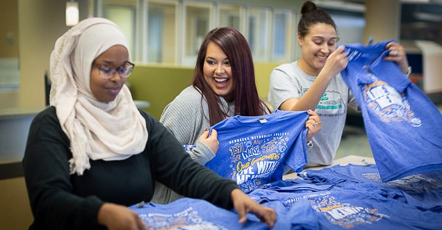 Jenny Christian (center) folds Homecoming T-shirts with a couple student ambassadors.