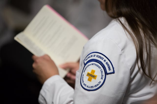 Nursing Student reading a book with their bachelor of science in nursing patch on their shoulder as the main focus of the photo
