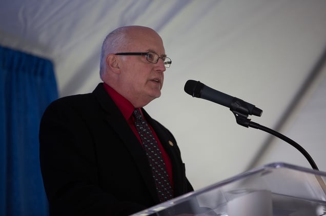 Dr. Dennis Joslin standing at a podium with a microphone welcoming attendees to Convocation