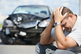 A distressed man with his totaled car in the background