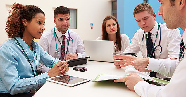 Five online doctor of education students sit at a table with laptops and tablets arranged around them, working together on class work. With an EdD in Public Health Policy, you'll work with doctors and policy makers to influence change in your community.