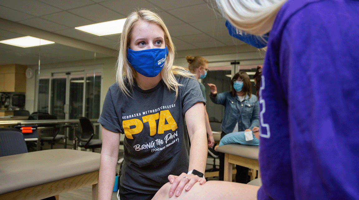 A Nebraska Methodist College physical therapist assistant student practicing therapeutic exercises with another student.