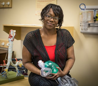 Kimberly, one of Nebraska Methodist College's respiratory care students holding a bag valve mask and smiling for the camera