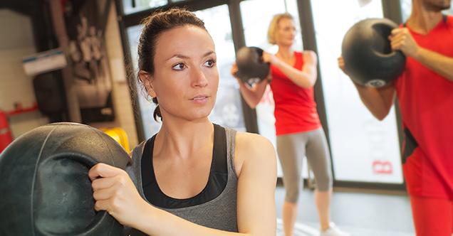 A woman holding a medicine ball in an exercise class.  New concentrations in NMC's Wellness & Health Promotion Management program allow for a focus in either Medical Fitness Management or Worksite & Community Wellness.