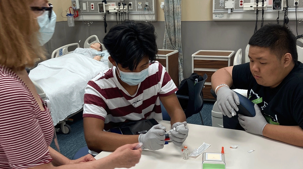 Two Upward Bound students learn how to give injections from a Nebraska Methodist Hospital faculty member. 