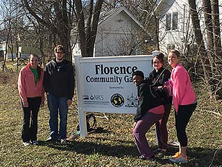 NMC students posing in front of a sign for Florence Community Garden