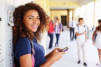 High school student leaning her back against her locker and smiling