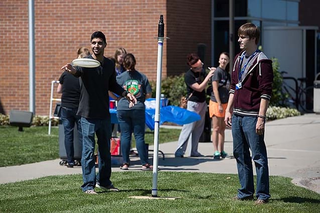 Two Nebraska Methodist College students throwing a frisbee at the Root Beer Kegger