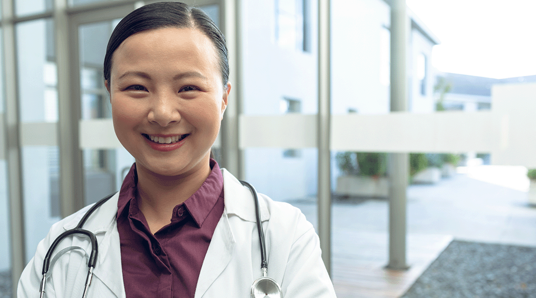 A nurse practitioner looks at the camera and smiles.