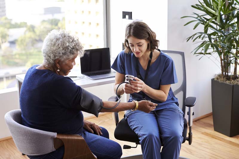 A medical assistant taking an elderly patient's blood pressure