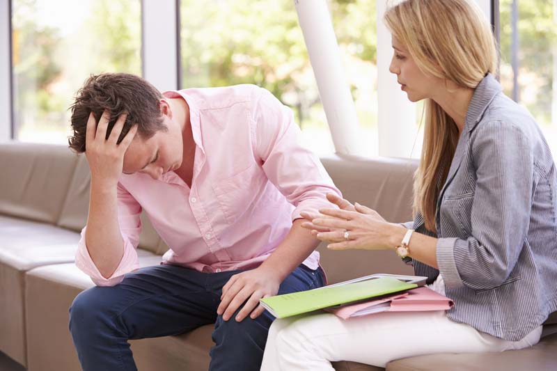 A stressed student holding his head. knowing the signs of when to transfer colleges can help. College can be a time of mixed feelings but transferring schools may help you feel at home.