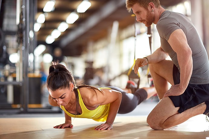 A medical fitness expert kneels near his client while she is doing modified pushups.Medical fitness is more than just general wellness or logging hours at the gym. It's about actively managing their lifestyles and lowering their living health risks.