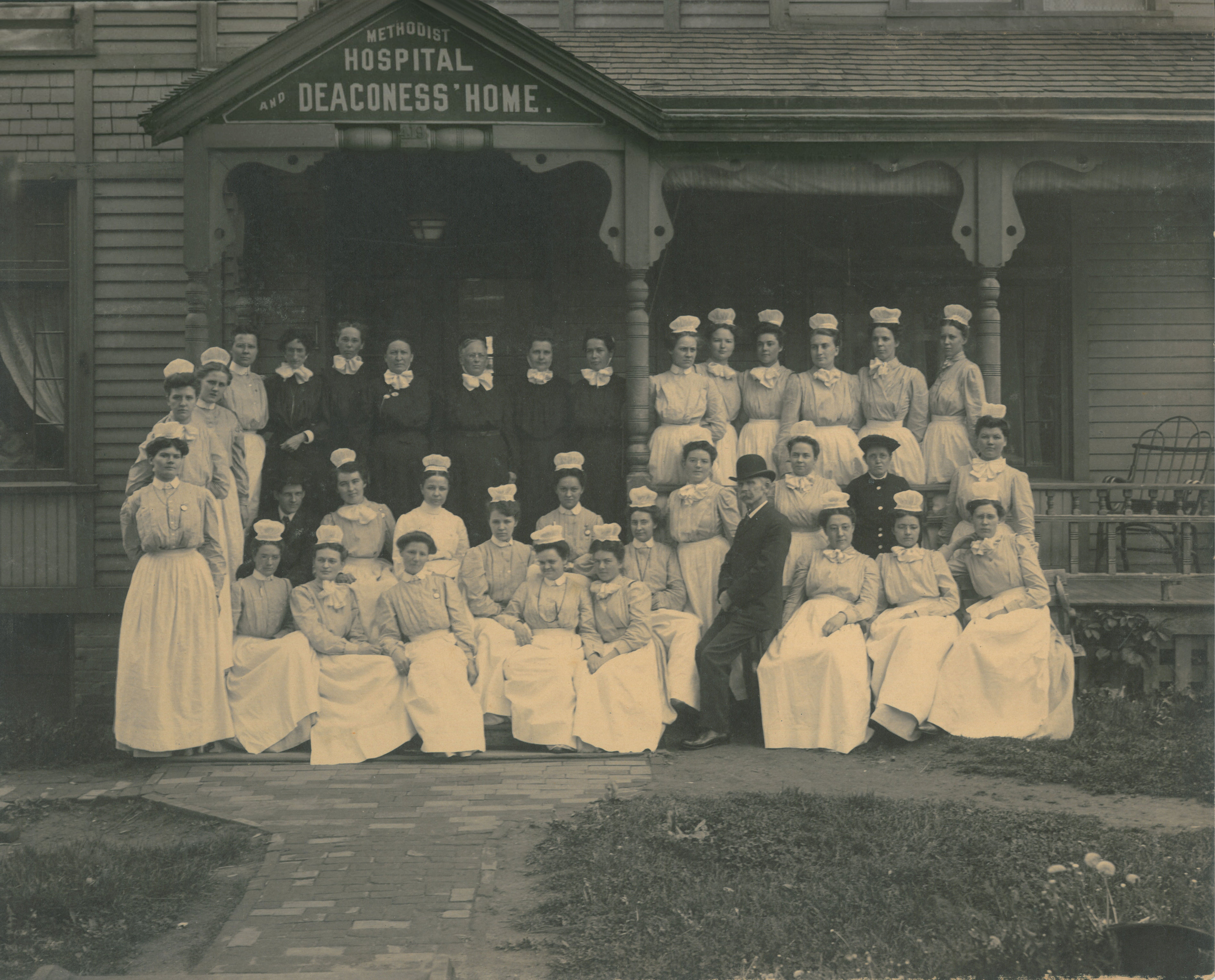 Black and white photo of one of the first classes of Nebraska Methodist College, set up in front of the Methodist Hospital and Deaconess' Home