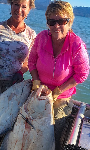 NMC alum Candy Rutledge and friend with one of several 40-pound halibut caught that day.