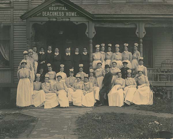 Sepia photo of deaconesses and nursing staff posed on steps of the Methodist Hospital and Deaconess' Home at 20th and Harney streets in Omaha. 