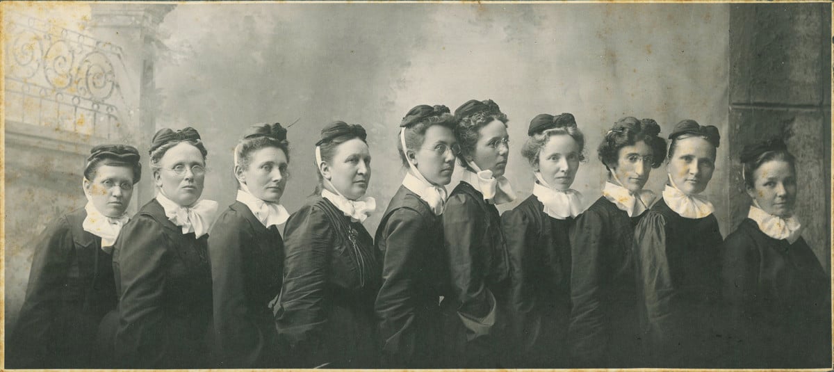 The first deaconesses who managed the original Nebraska Methodist Hospital  and its school of nursing. Photo of 10 women dressed in black uniforms with white collars - 1892 .