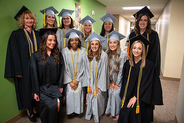 NMC grads pose in their caps and gowns. 