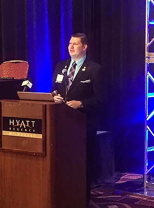 AAMN President Blake Smith , an NMC alumnus, at the podium addressing the 2018 AAMN  Conference attendees.
