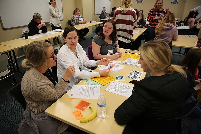 A group of students works as a "family" and discusses their strategy for the poverty simulation.