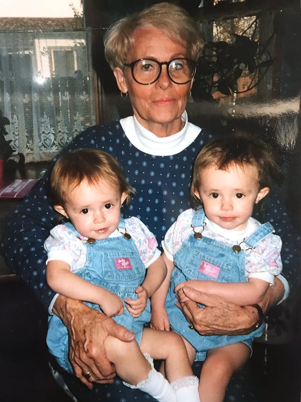 Grandma with the twins as babies, dressed in identical outfits.