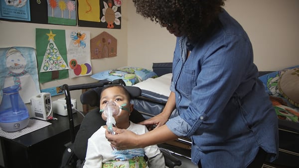 Latoya holding a respiratory mask on her son