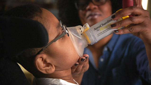 Respiratory therapist Latoya Sharp places mask on her son. 