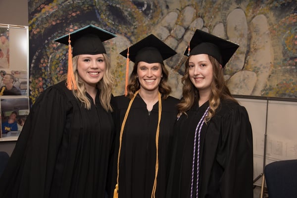 A trio of new graduates pose for a photo.
