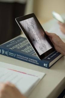 A radiologic technologist examining an x-ray on an iPad