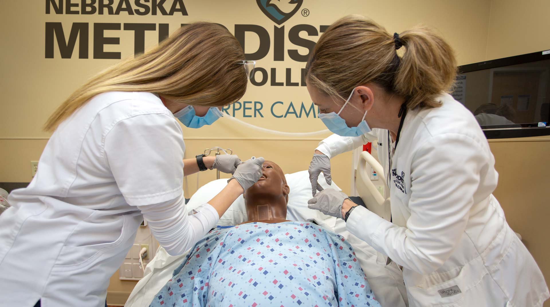Nursing student and instructor work on opening the airway of a manikin in class at Nebraska Methodist College