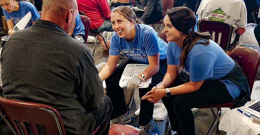 Master of Occupational Therapy students Jami Neckoliczak and Katelyn Leming provide a foot assessment  at the Foot Care Clinic for the Homeless held at Open Door Mission.